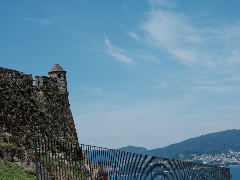 a tall stone wall next to a body of water