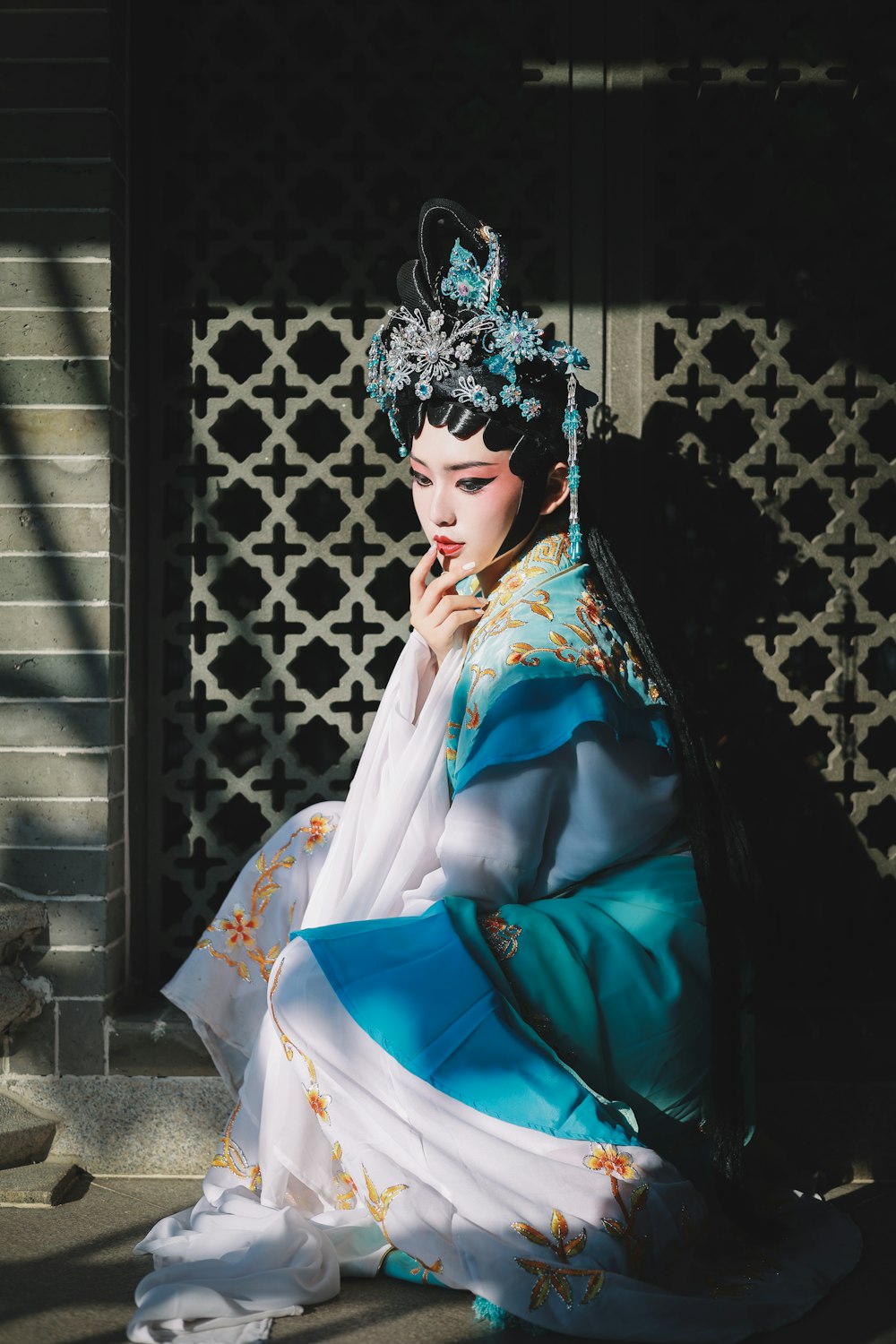 a woman in a blue and white dress sitting on the ground