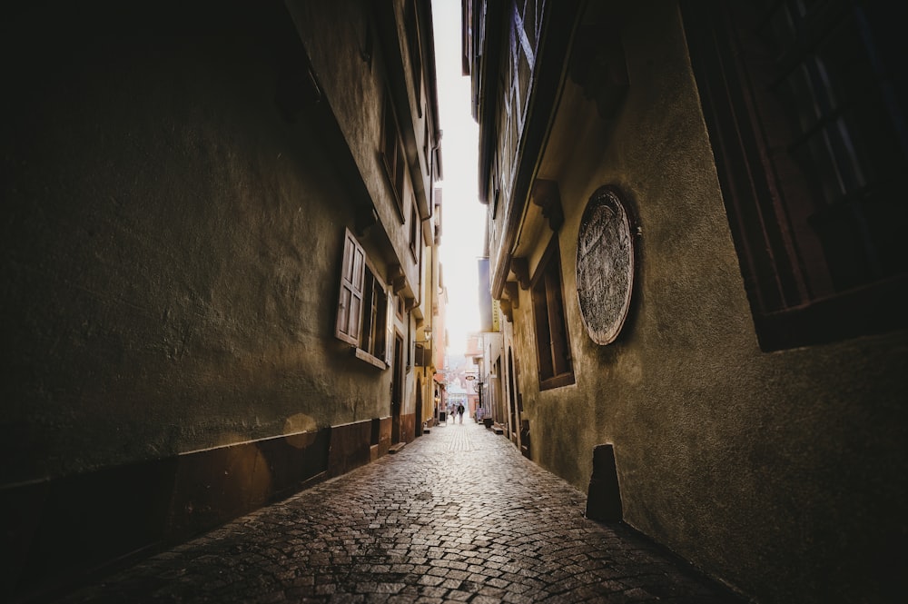 a narrow alley with a clock on the wall