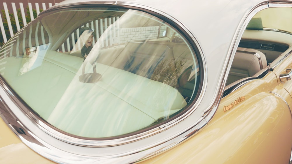 a man sitting in a car with his reflection in the side view mirror