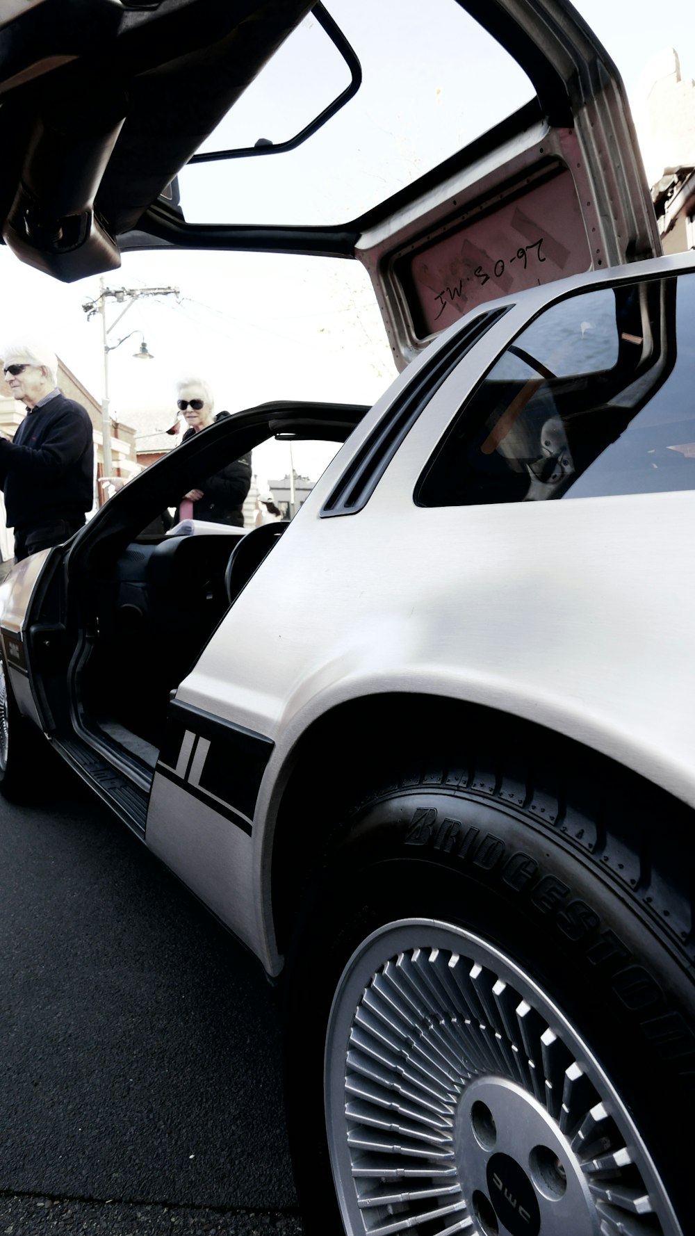 a white car with its door open sitting on the side of the road