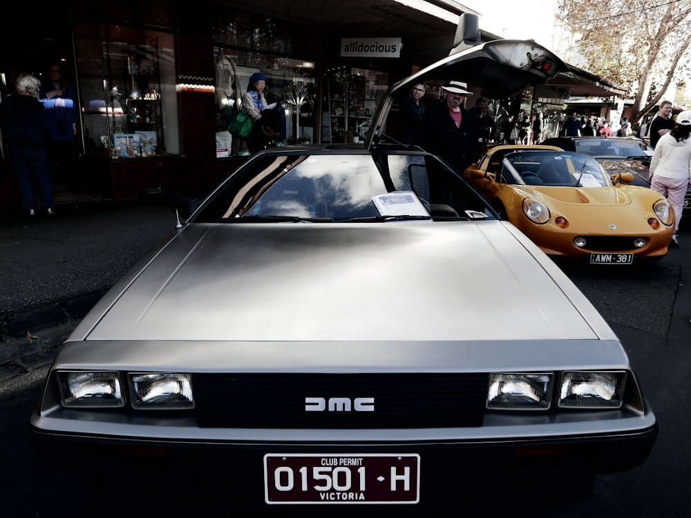 a silver car parked next to a yellow car on a street