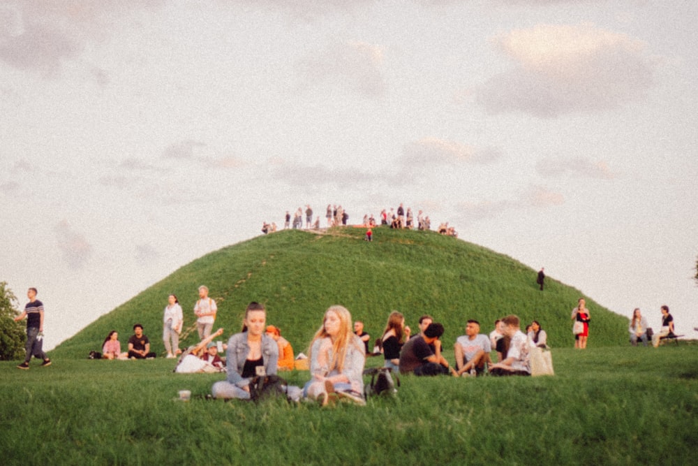 a group of people sitting on top of a lush green hillside