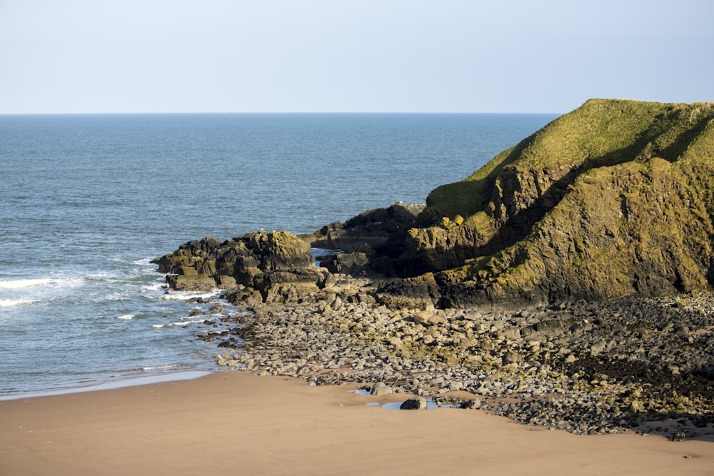 a sandy beach next to a rocky cliff