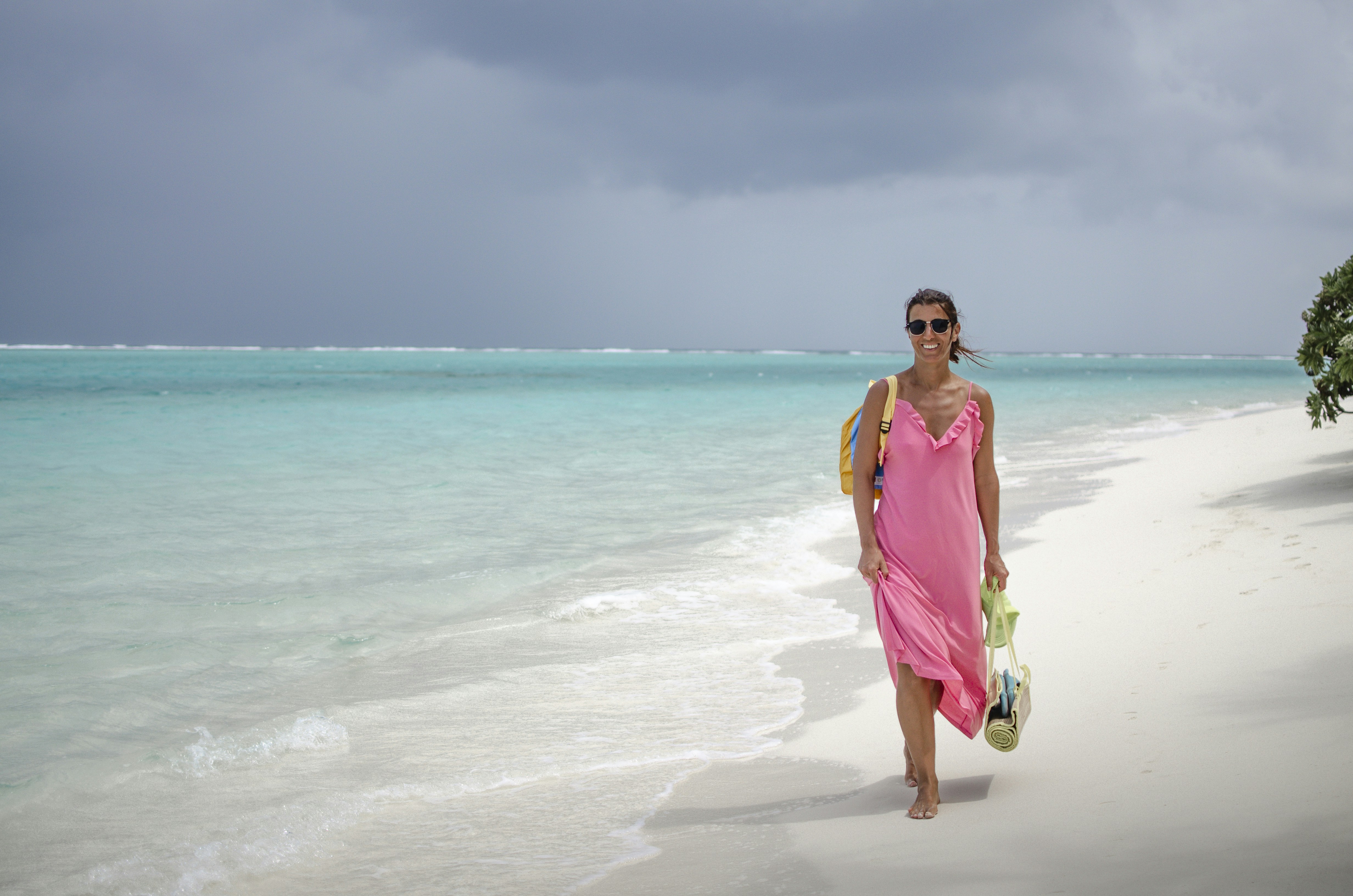 a woman in a pink dress is walking on the beach