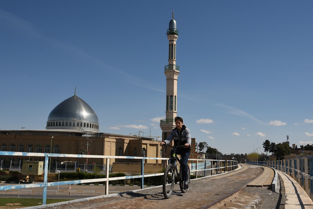 a man riding a bike down a road next to a tall building