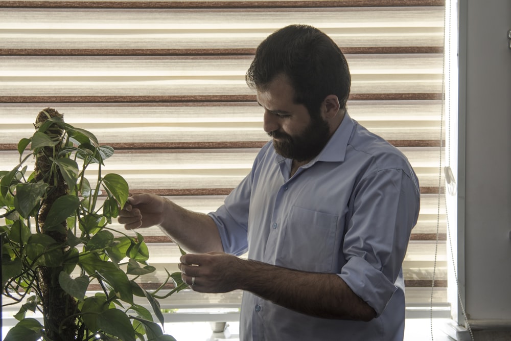 a man standing next to a plant in front of a window