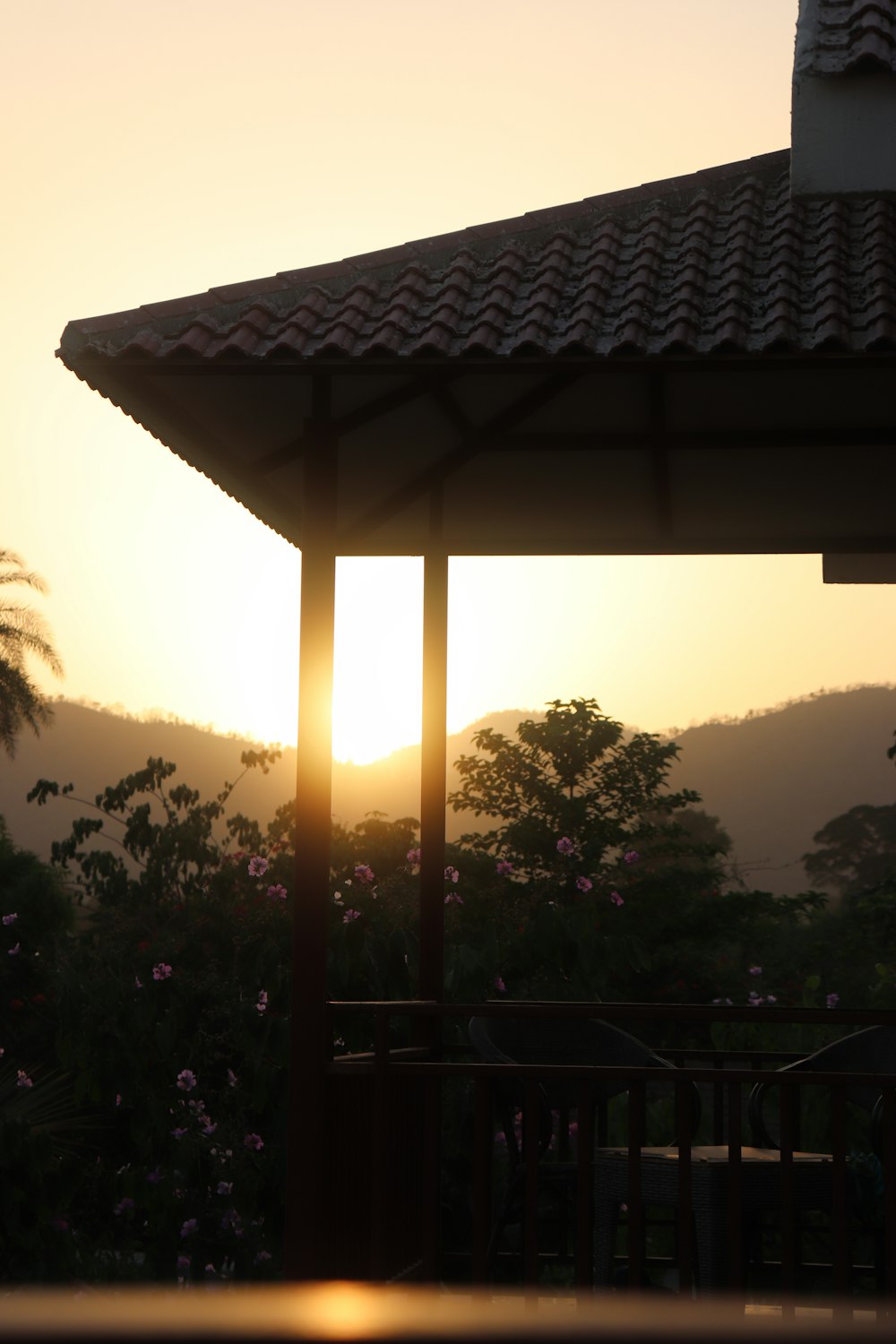 the sun is setting over the mountains behind a gazebo