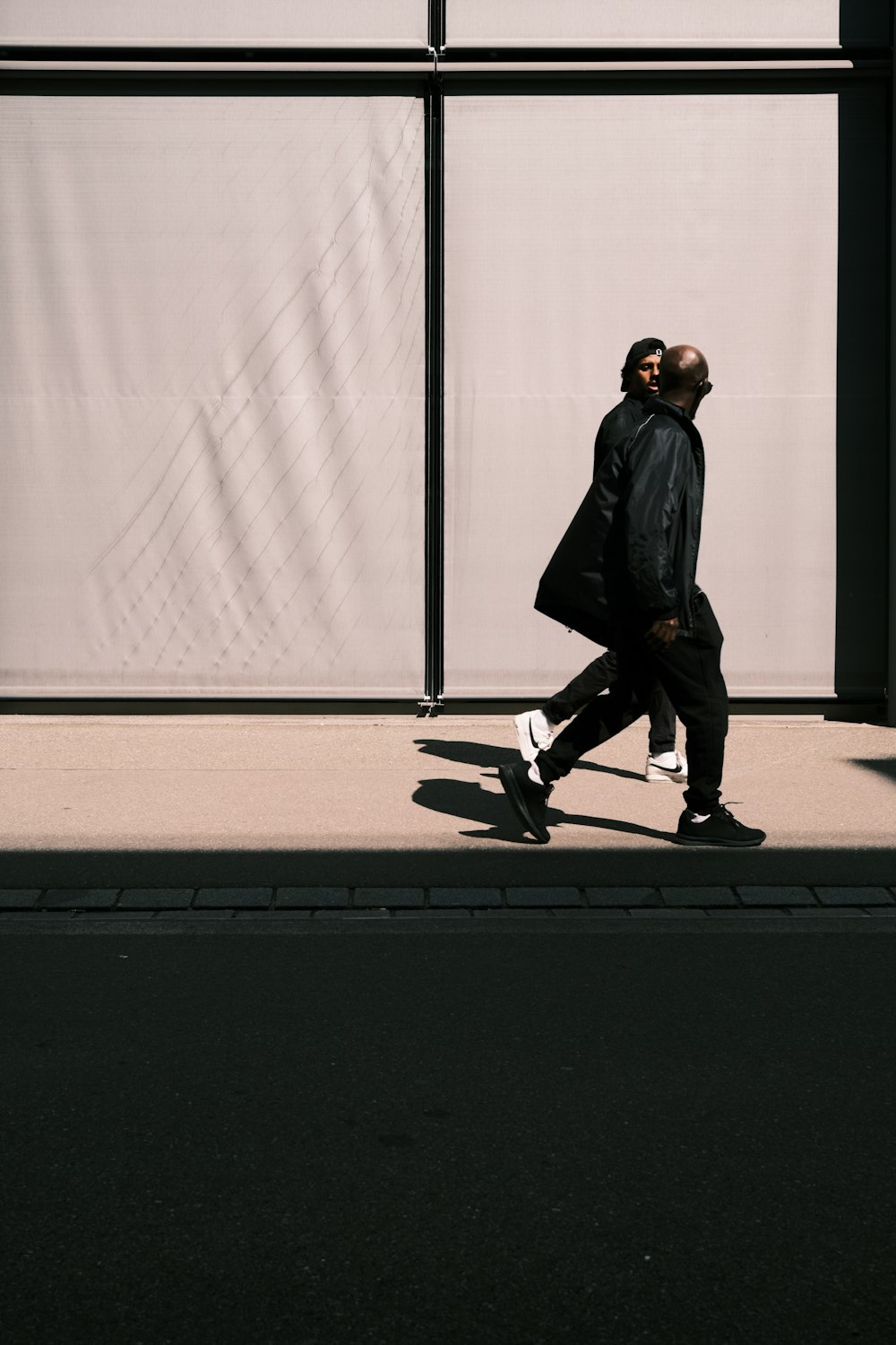 a man walking down a street next to a tall building