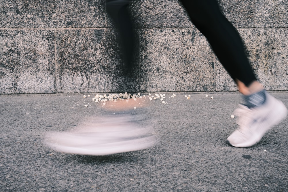 a person walking on a sidewalk near a wall