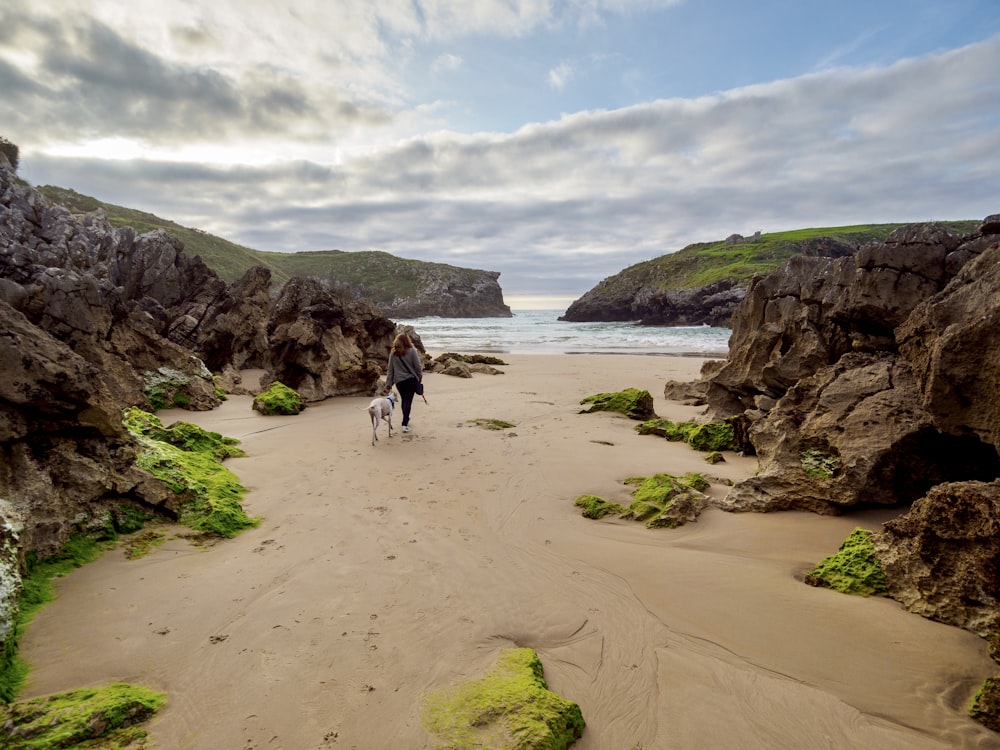 a couple of people walking down a sandy beach