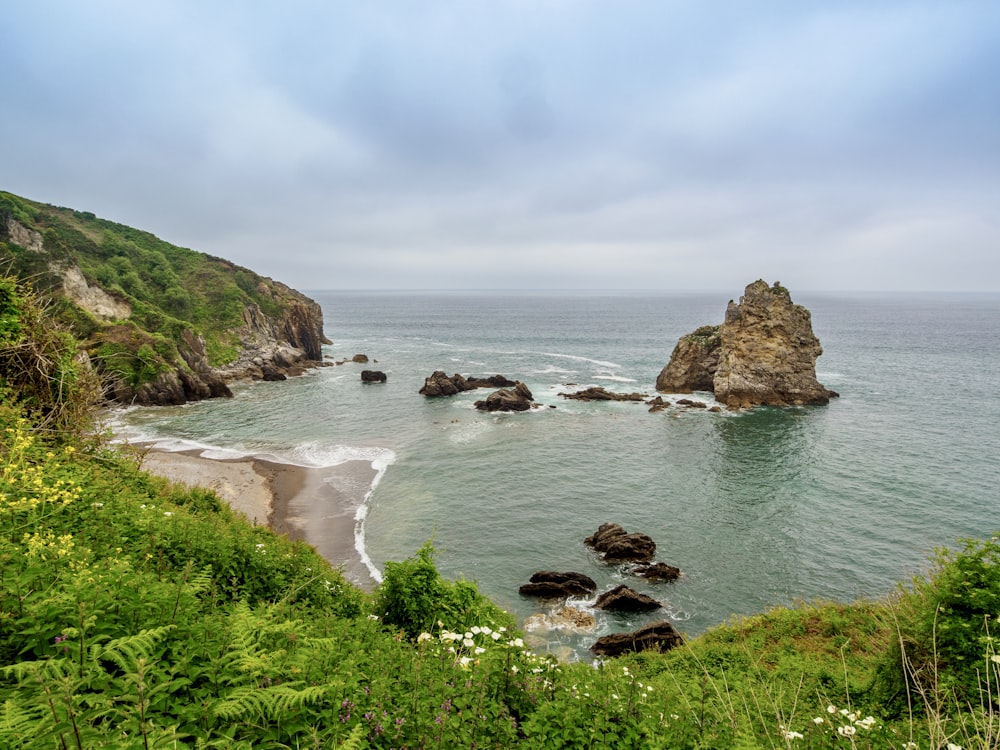 a view of a beach with a rock outcropping in the water