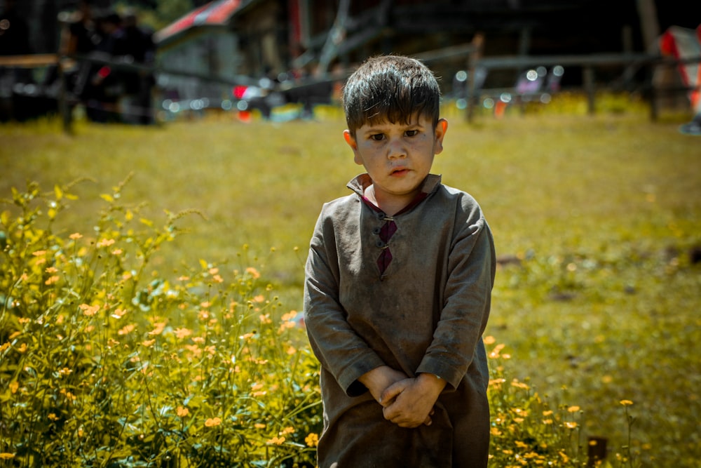 a young boy standing in a field of yellow flowers