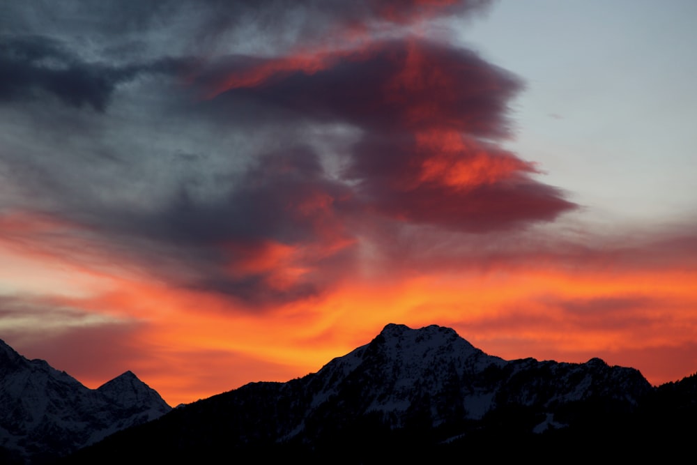 a red and orange sky with a mountain in the background