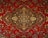 An intricate and detailed Persian rug features a central medallion with ornate floral and geometric patterns. The design is symmetrical and rich in detail, showcasing a traditional style with elaborate motifs.