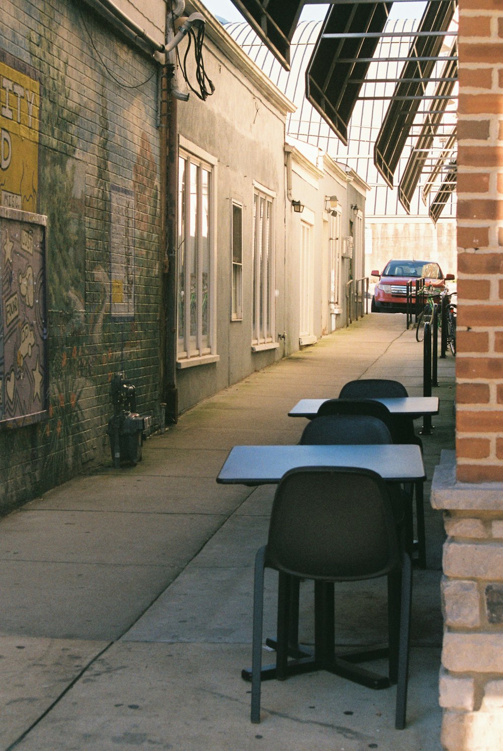 a sidewalk lined with tables and chairs next to a building