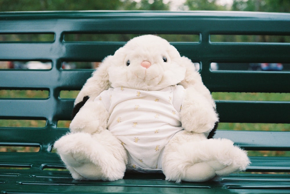 녹색 벤치 위에 앉아 있는 흰 박제 토끼