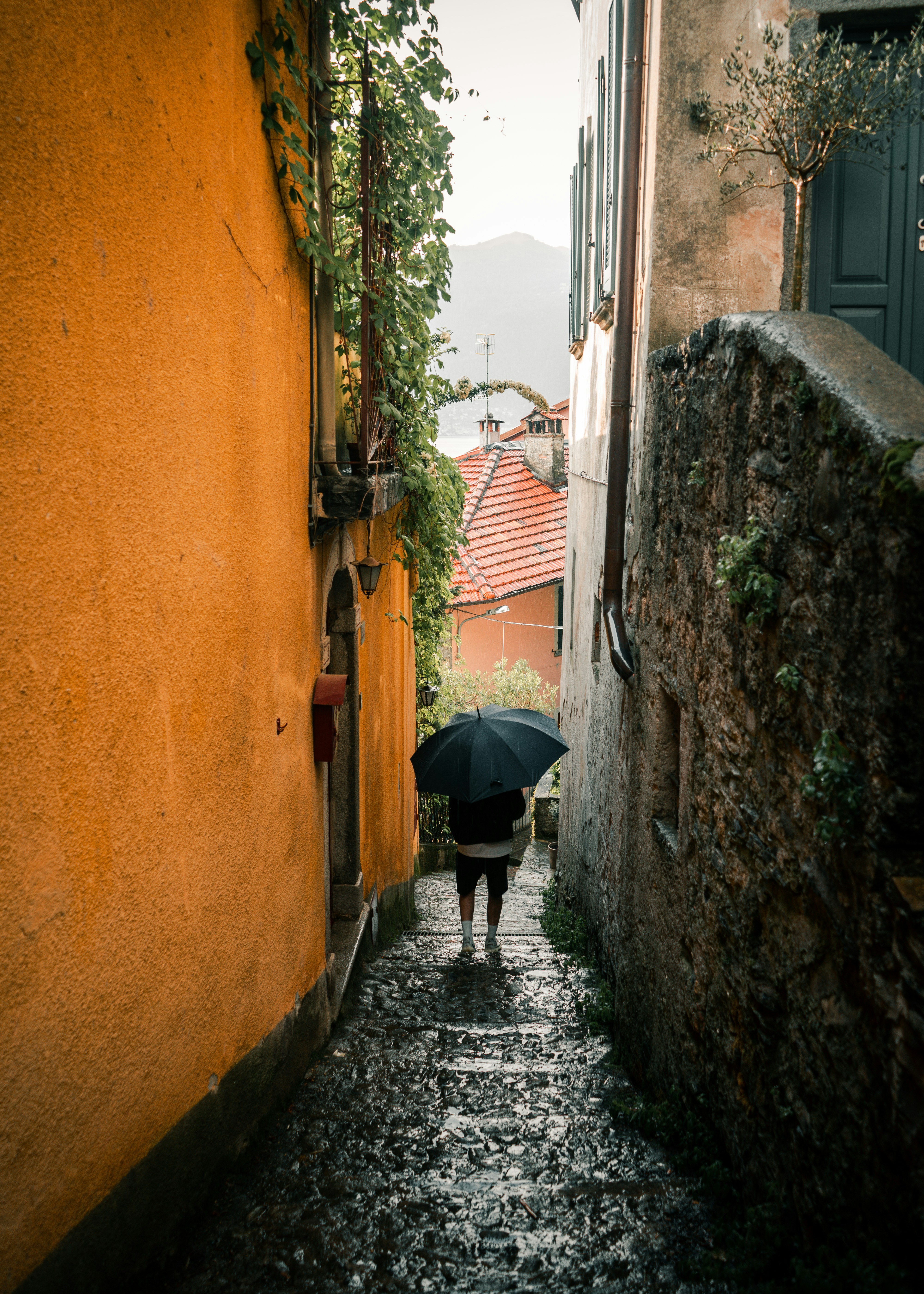 Una persona con un paraguas camina por una calle empedrada