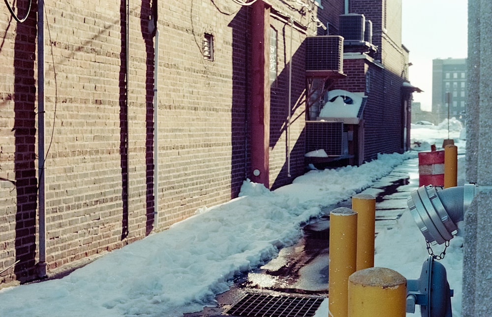 a snow covered street next to a brick building