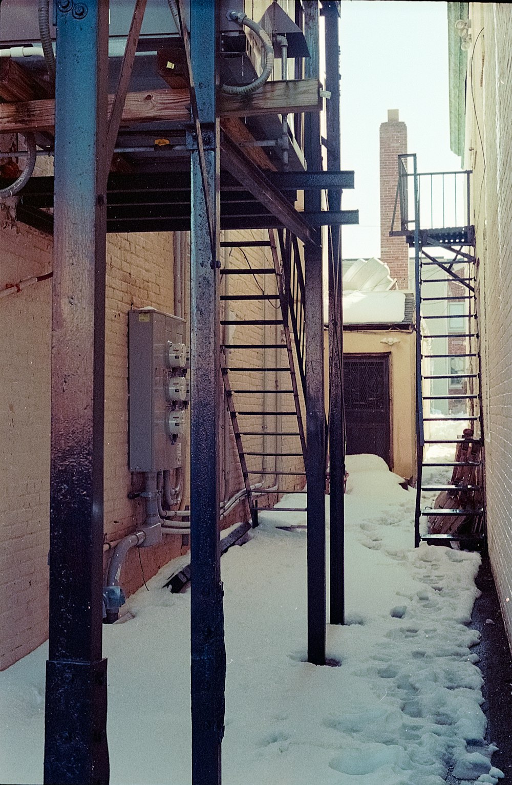 a snow covered alley way next to a brick building