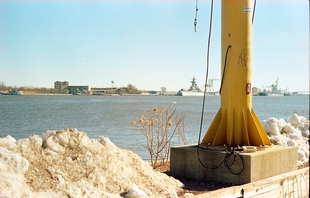 a yellow buoy sitting next to a body of water