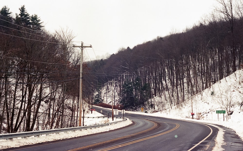 a snow covered road in the middle of a wooded area