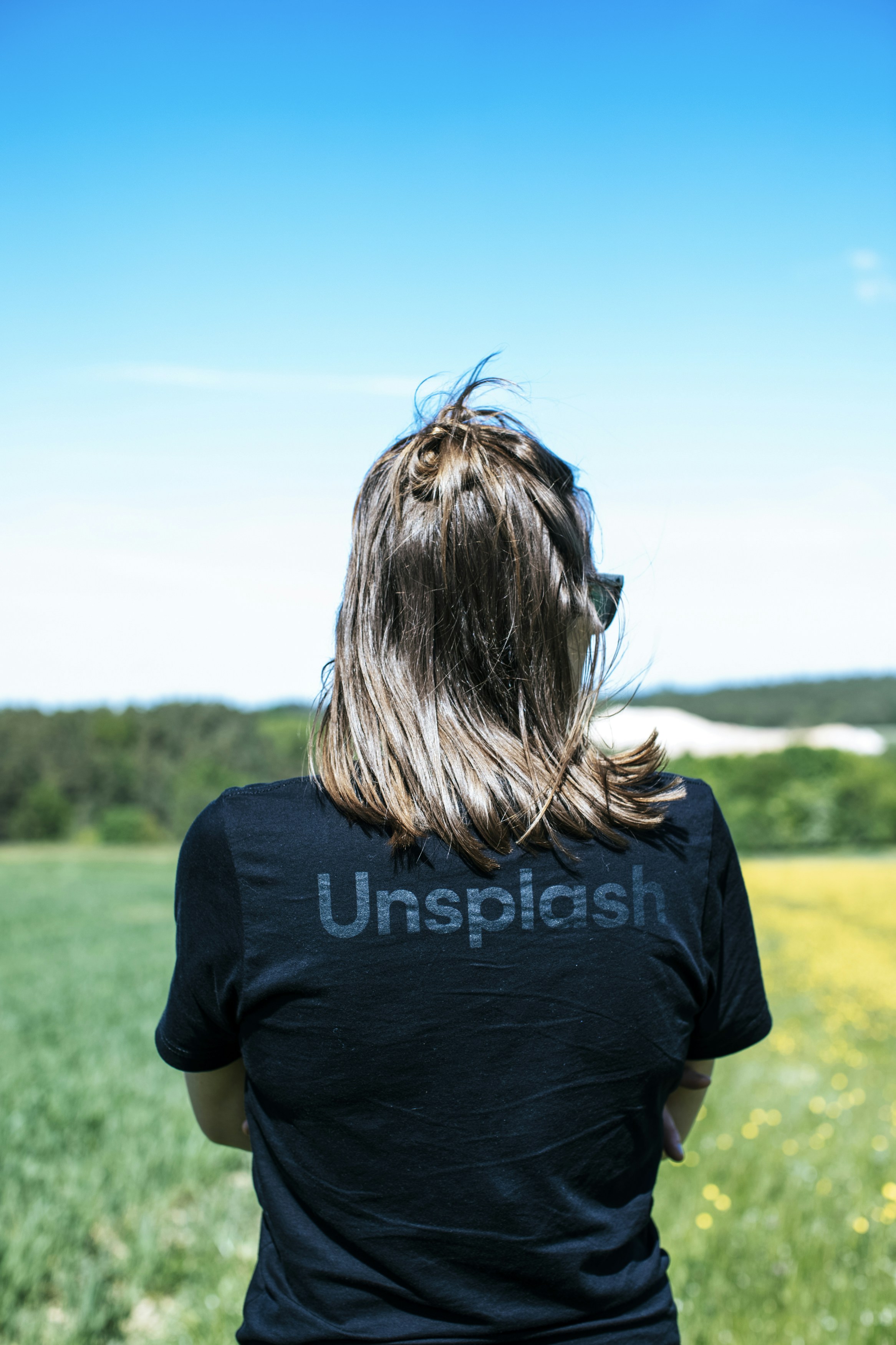 カメラに背を向けて野原に立つ女性