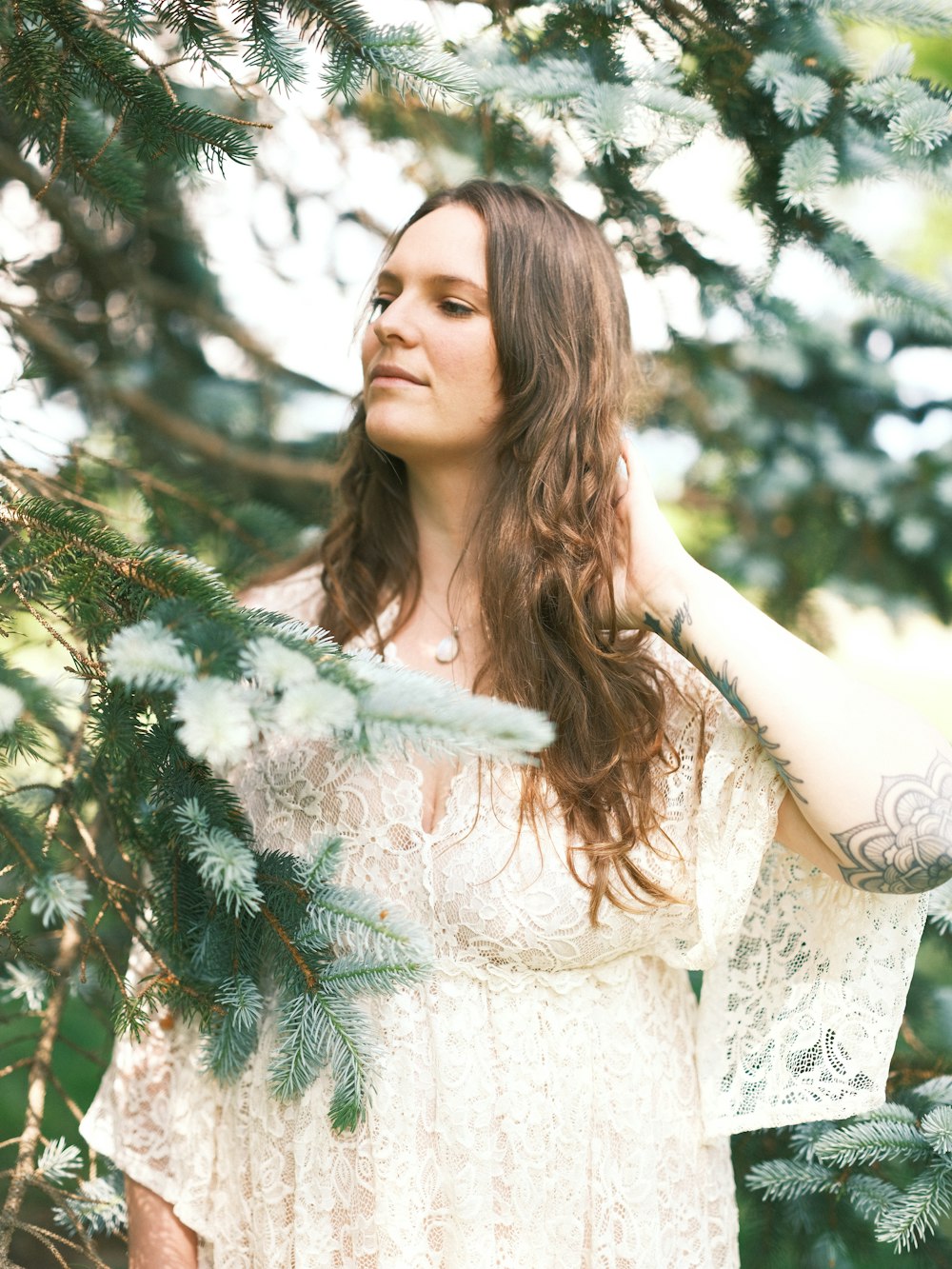 a woman in a white dress standing under a tree