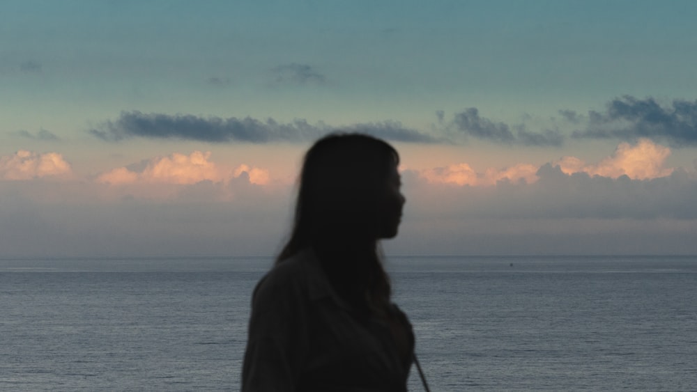 a woman standing in front of a body of water