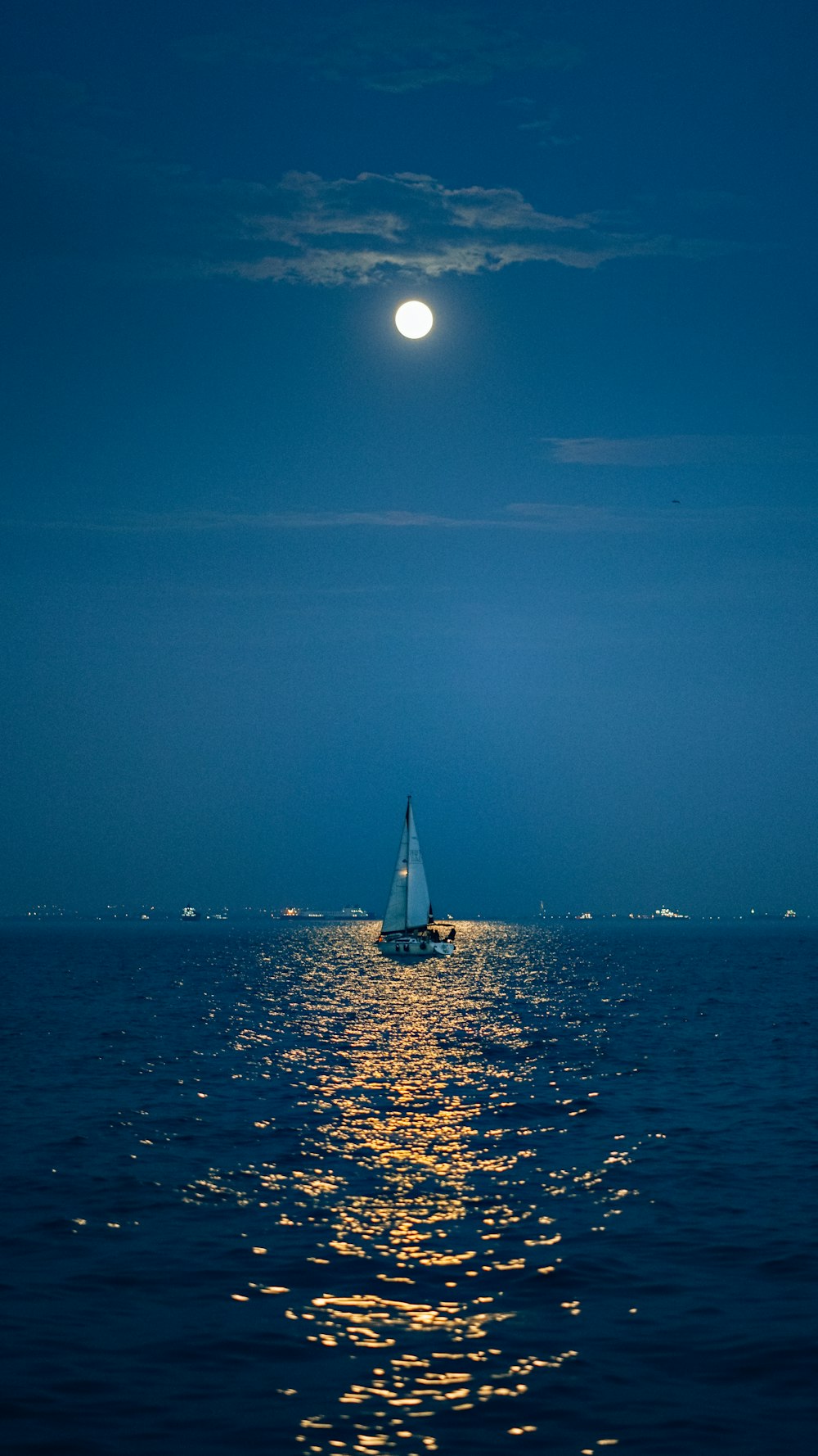 a sailboat in the ocean with a full moon in the background