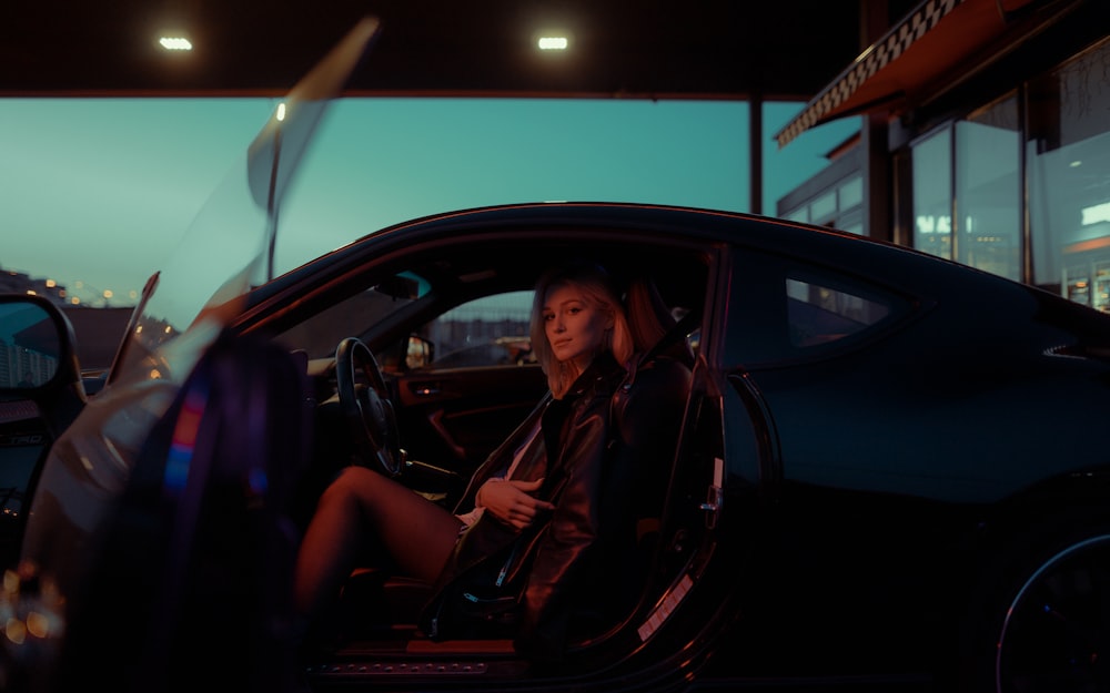 a woman sitting in a car in a parking lot