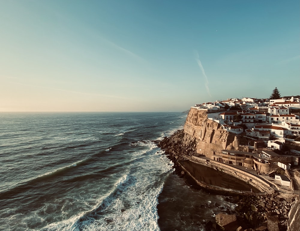 a view of a beach with houses on the cliff