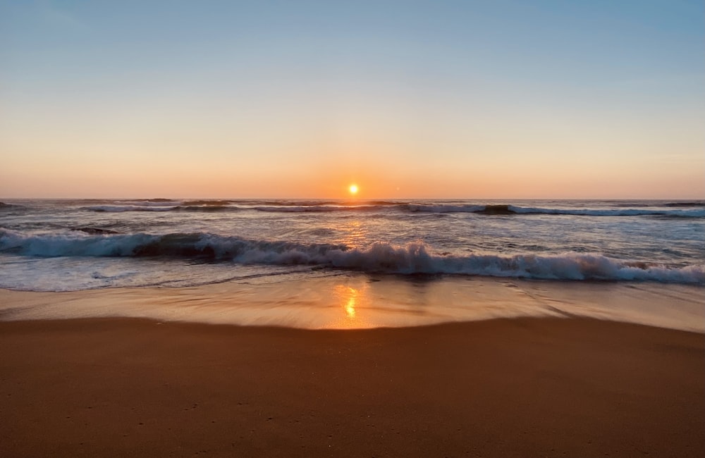 the sun is setting over the ocean waves