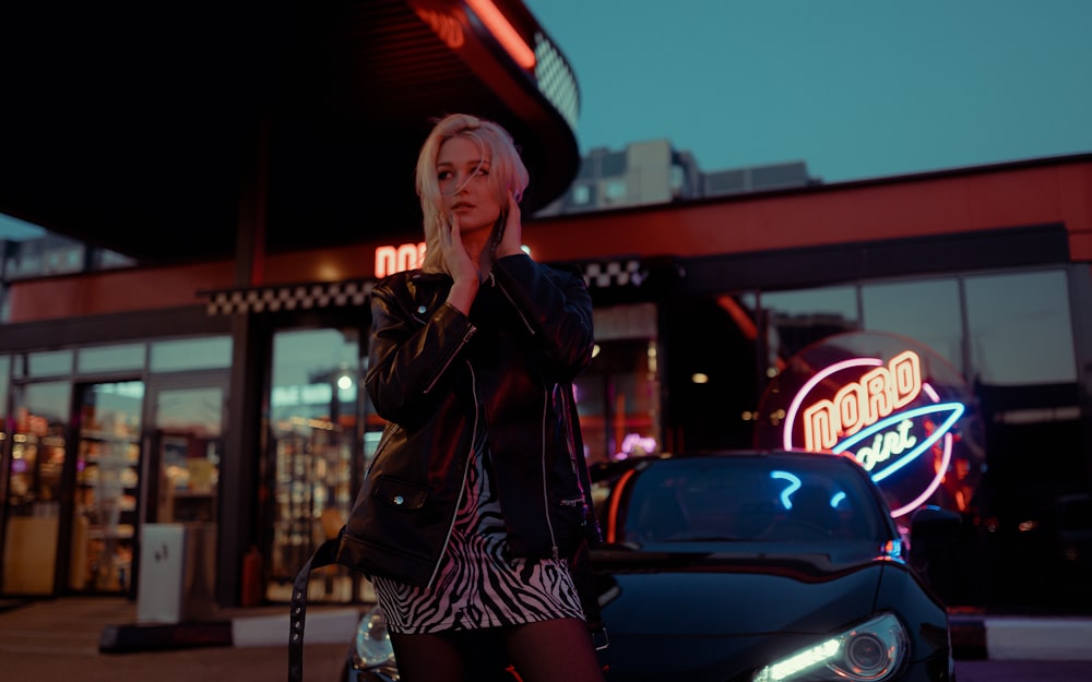 a woman standing in front of a car talking on a cell phone