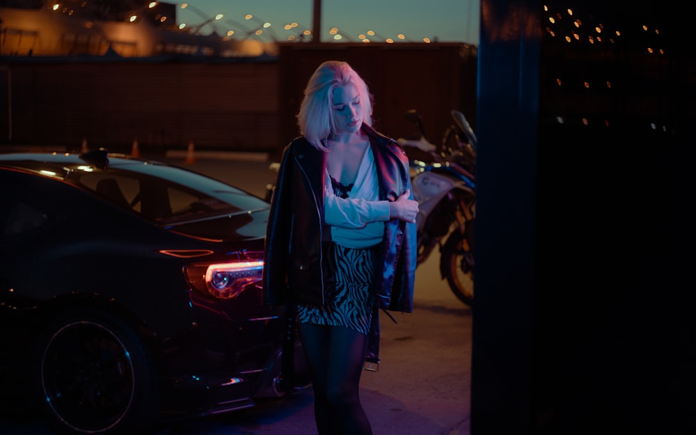 a woman standing next to a parked car