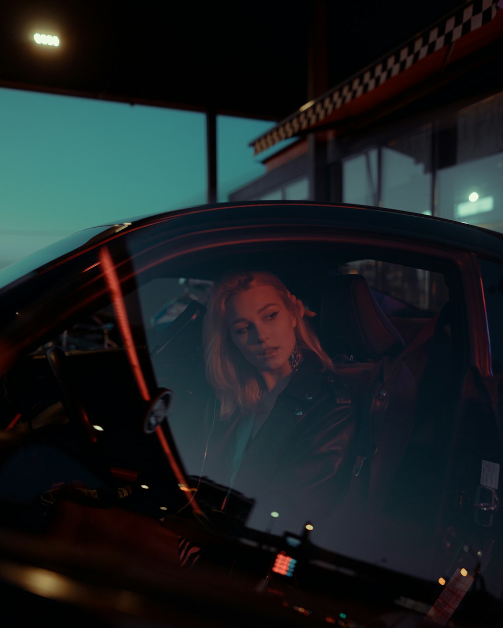 a woman sitting in a car at night