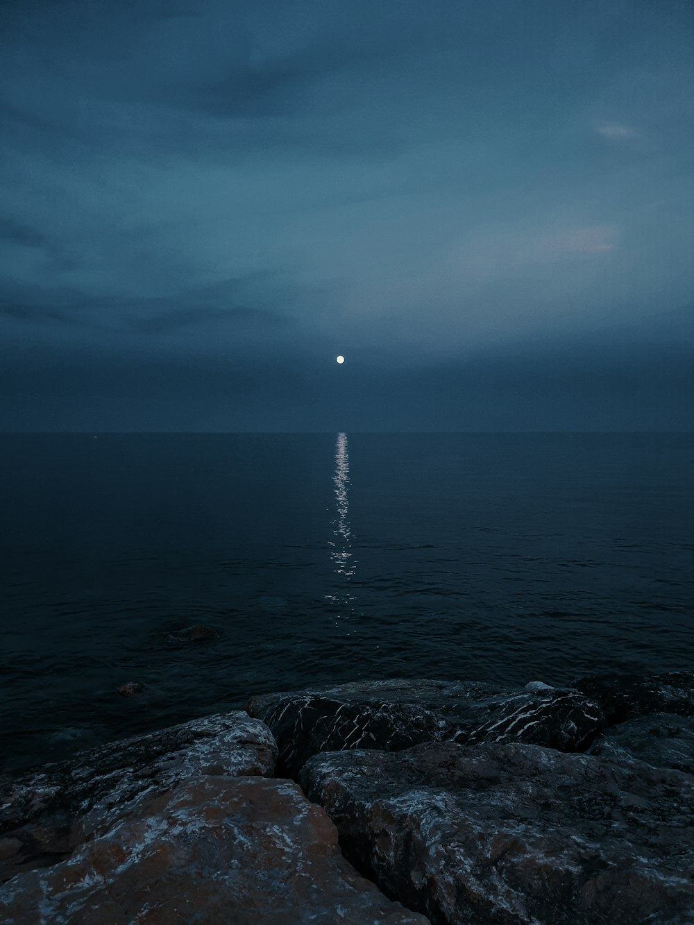 a full moon is seen over the ocean