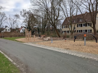 A community playground surrounded by trees and walking paths at Vrindavan Dhaam.