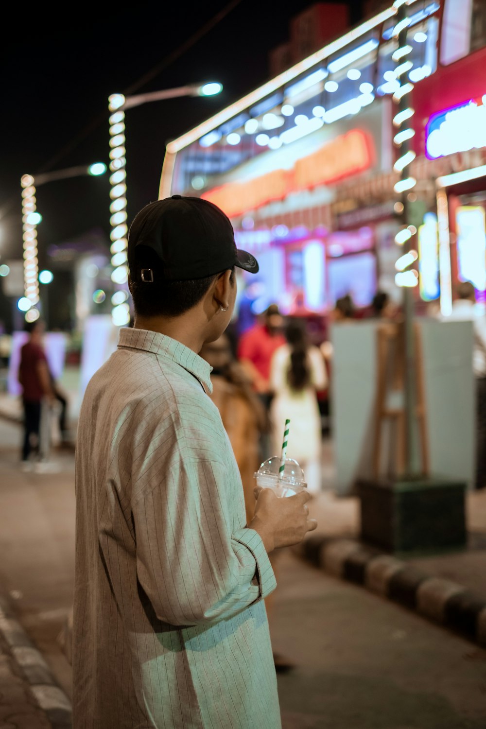 a man standing on the side of a street holding a drink