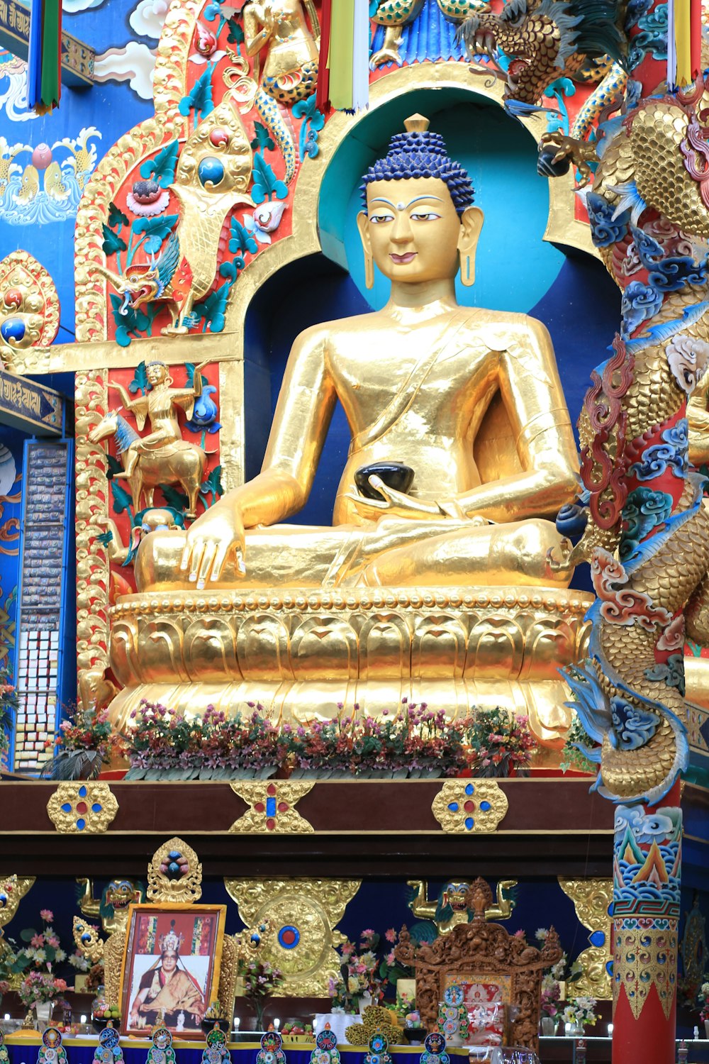 a golden buddha statue sitting in front of a blue wall
