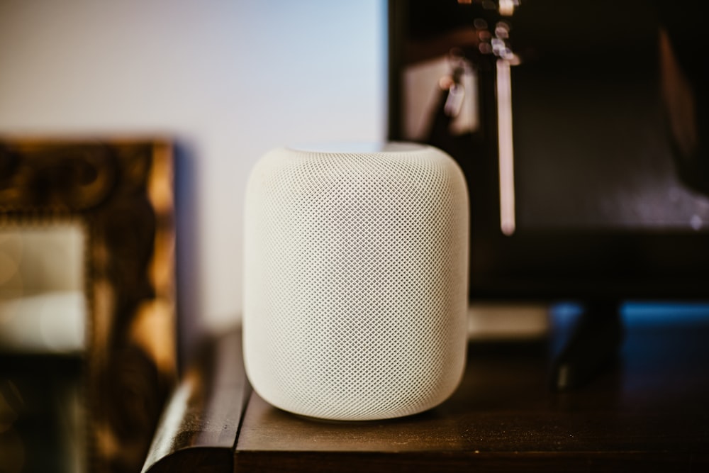 a white speaker sitting on top of a wooden table