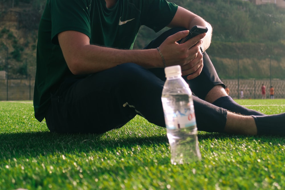 a man sitting on the grass with a bottle of water