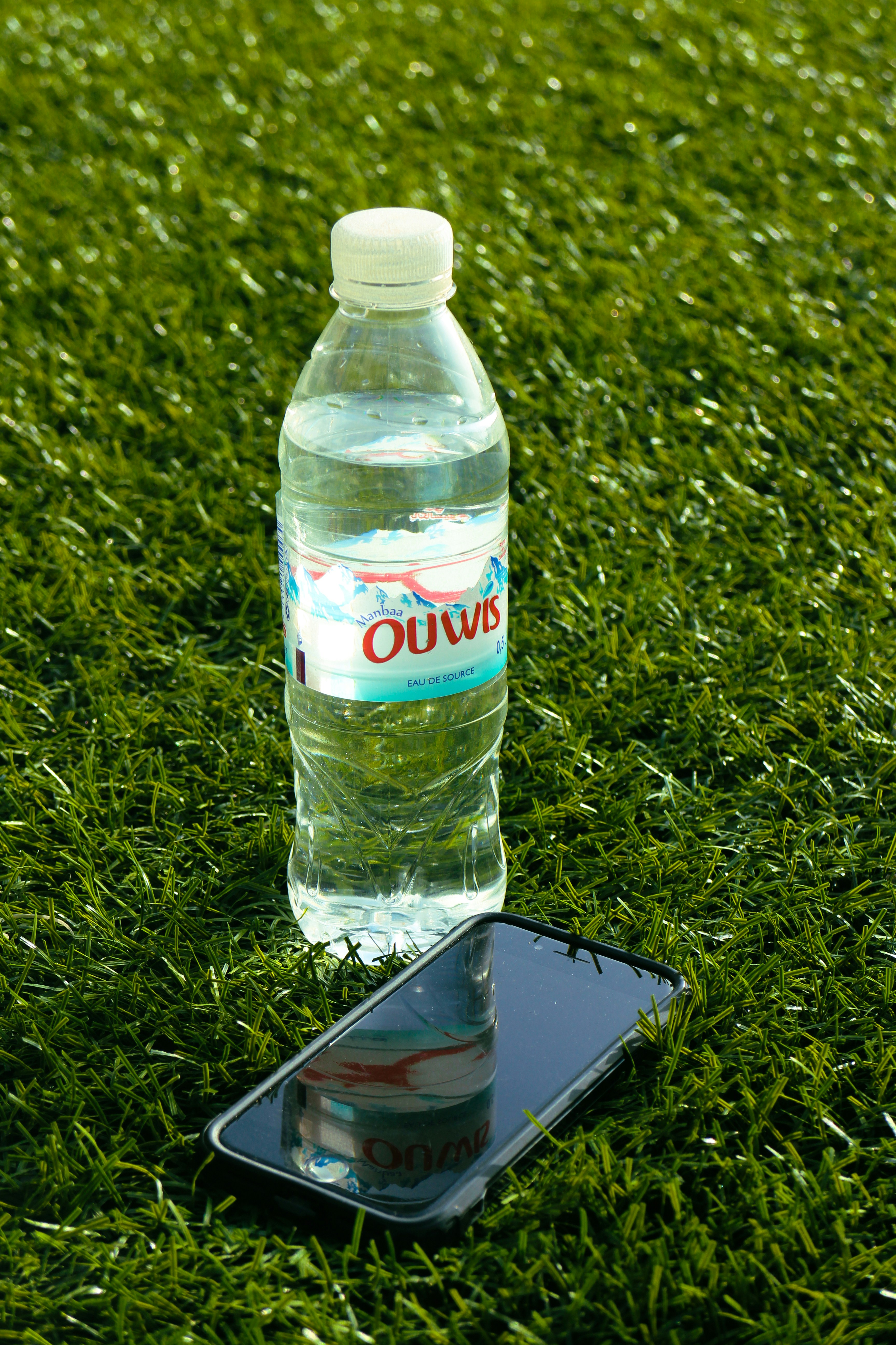 a bottle of water sitting on top of a cell phone