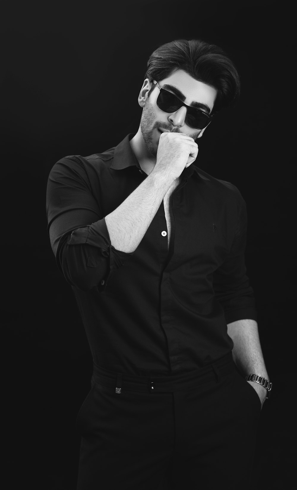 Un homme en chemise noire et lunettes de soleil