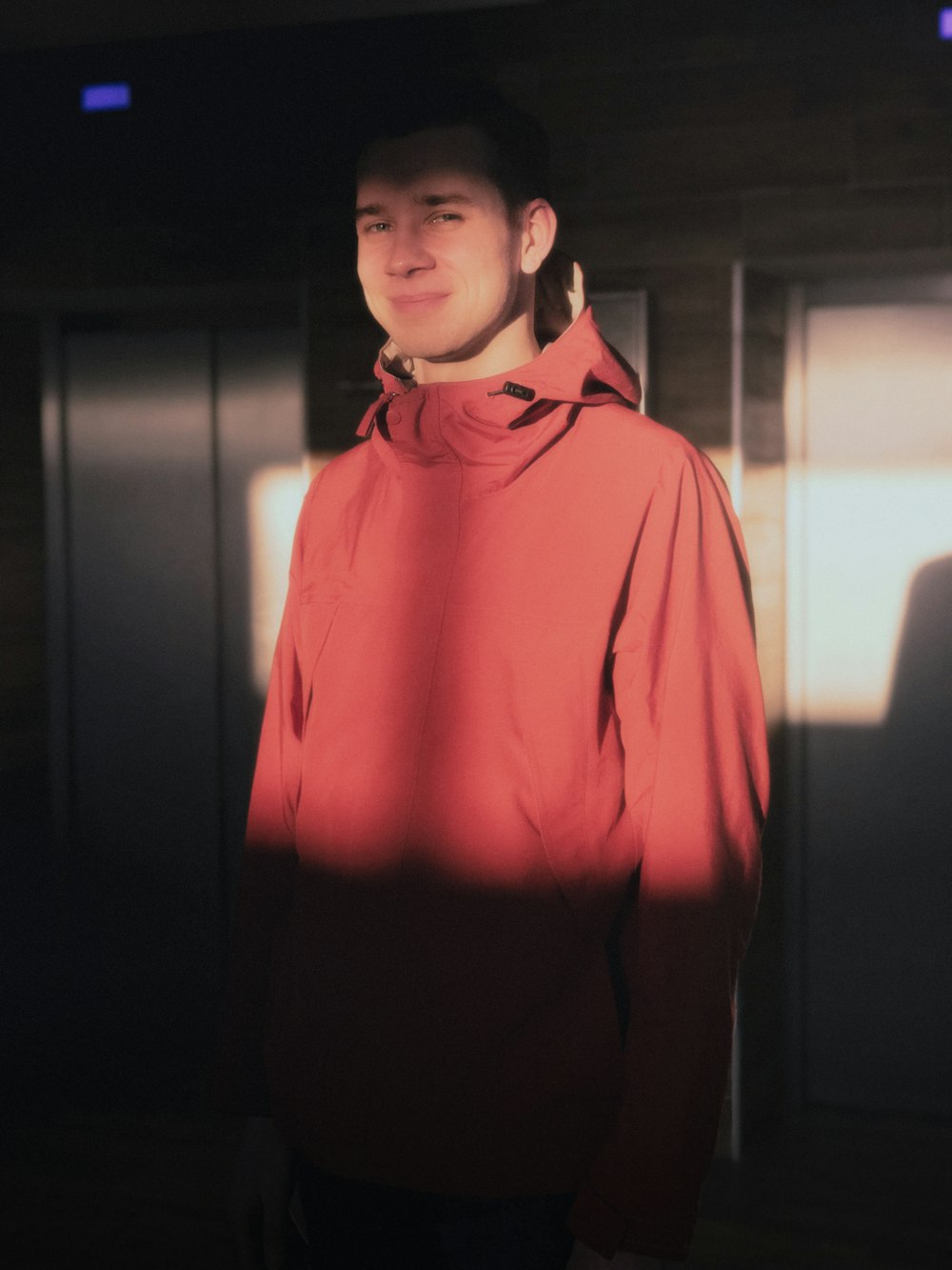 a man in a red jacket standing in a room