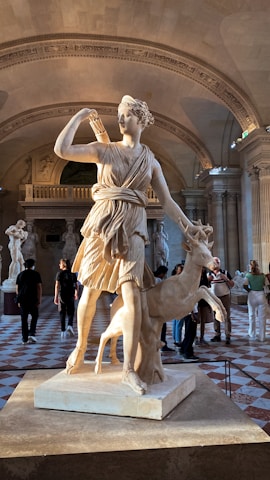 a statue of a woman standing next to a deer