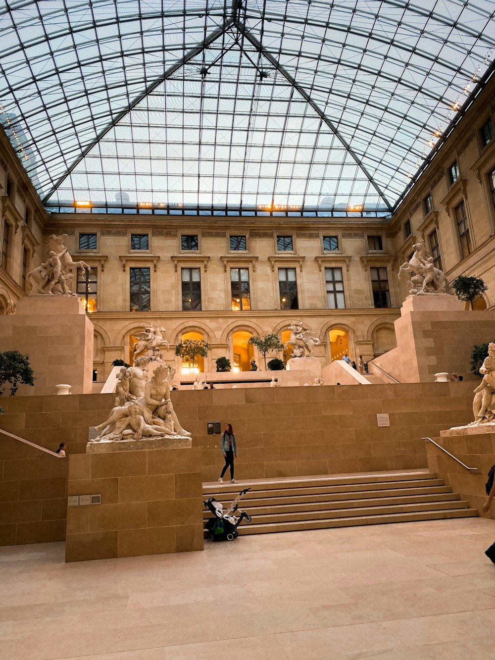 a large building with a glass roof and statues
