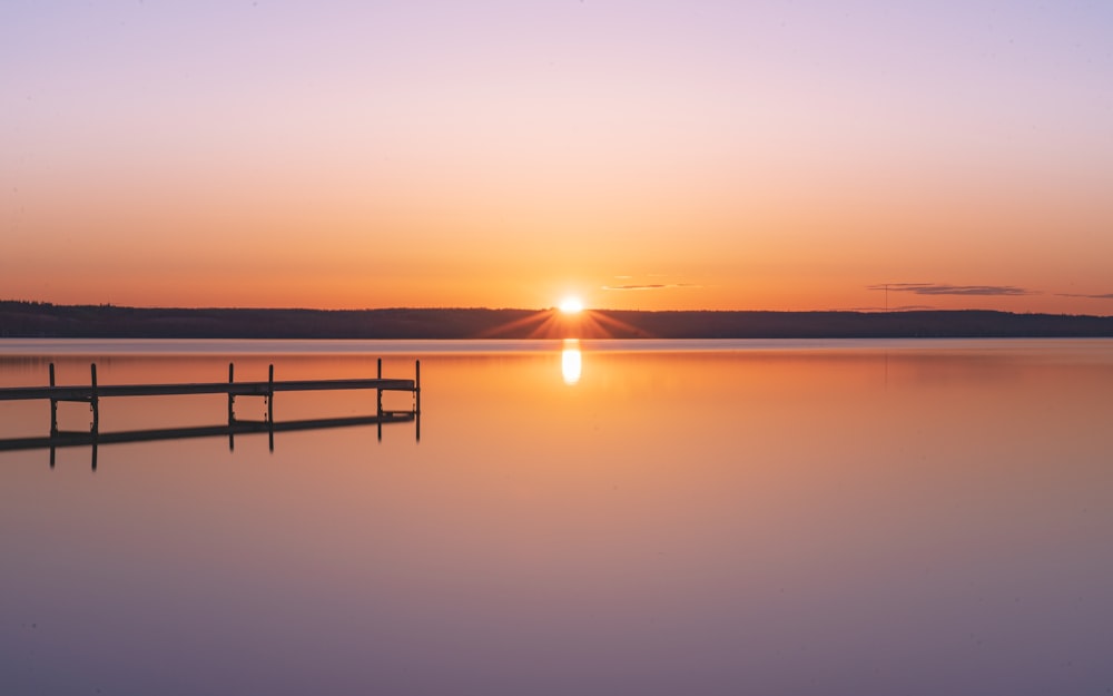 the sun is setting over a calm lake