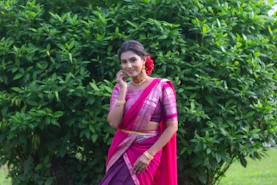a woman in a pink and purple sari talking on a cell phone