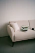 Laptop on a cream sofa with a pillow.